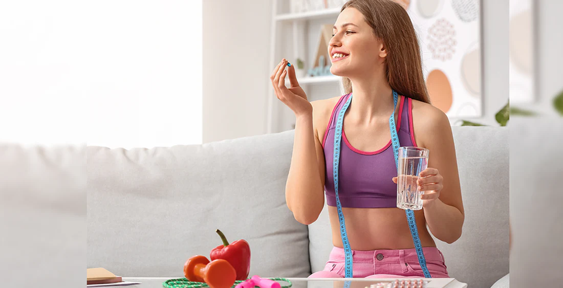 A woman is taking weight loss pills with a glass of water.